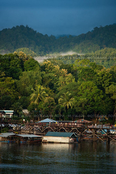 Kanchanaburi, Thailand, June 29, 2019 : Beautiful sunrise scene in early morning at old an long wooden bridge at Sangklaburi,Kanchanaburi province, Thailand. Редакционное фото, агентство Ingram Publishing / Фотобанк Лори