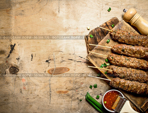 Kebab with green onions and hot sauce. On a wooden table.. Kebab with green onions and hot sauce. Стоковое фото, агентство Ingram Publishing / Фотобанк Лори