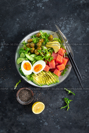 Ketogenic, paleo diet lunch bowl with salted salmon fish, lemon, avocado, olives, boiled egg, cucumber, green lettuce salad and chia seeds, healthy food trend, top view. Стоковое фото, агентство Ingram Publishing / Фотобанк Лори