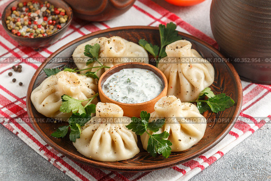 Khinkali - Georgian dumplings with meat and parsley in a ceramic dish with a sauce of sour cream and greens. Selective focus. Стоковое фото, фотограф Виктория Панченко / Фотобанк Лори