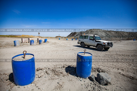 Khromtau, Aktobe region, Kazakhstan - May 06 2012: gold mine. Hand-made road balustrade of plastic barrel with concrete. Off-road car on background.. Редакционное фото, фотограф Alexey Rezvykh / Фотобанк Лори