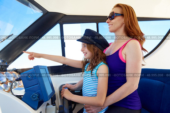 Kid girl pretending be a captain sailor cap with her mother in boat indoor. Стоковое фото, агентство Ingram Publishing / Фотобанк Лори