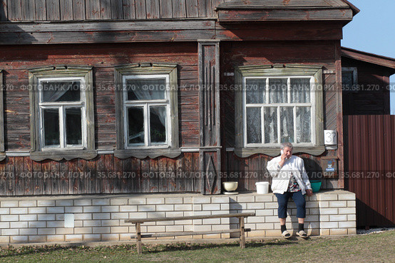 Кидекша, женщина на завалинке своего дома (2021 год). Редакционное фото, фотограф Дмитрий Неумоин / Фотобанк Лори