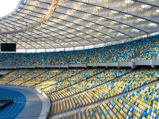 KIEV, UKRAINE - July 19, 2018. National Sports Complex Olimpiysky - the inside part with a football field, tribunes in a blue and yellow colors. Aerial view from drone in a summer time.. KYIV, UKRAINE - July 19, 2018. Panoramic view of construction of the stadium roof, tribunes with yellow and blue seats of NSC Olimpiysky. Редакционное фото, агентство Ingram Publishing / Фотобанк Лори