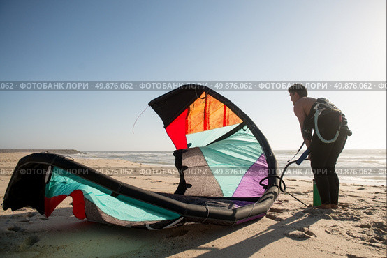 Kitesurfer prepating his equipment on a beautiful sunset at the beach. Стоковое фото, агентство Ingram Publishing / Фотобанк Лори