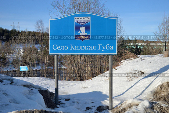 Knyazhaya Guba Village, urban settlement of Zelenoborsky, Kandalaksha district, Murmansk region, March 23, 2024: Banner Knyazhaya Guba village with coat of arms on bank of Knyazhegubskaya hydroelectric power station canal. Редакционное фото, фотограф Алексей Антипов / Фотобанк Лори