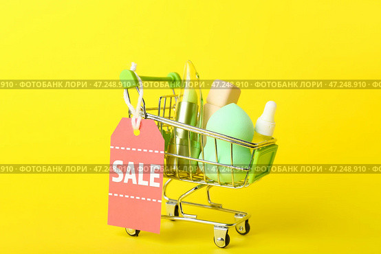 Корзина с косметическими продуктами и биркой продажи на желтом фоне. Стоковое фото, фотограф Pixel_shot / Фотобанк Лори