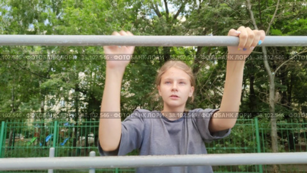 Красивая девочка подросток со светлыми волосами поднимается вверх по металлической лестнице. Шведская стенка  на детской площадке в городском парке. Ребенок играет на площадке возле школы. Турники для спортивных занятий. Beautiful teen girl with blonde hair climbs up a metal ladder. Wall bars on the playground in the city park. Child is playing on the playground near the school. Horizontal bars for sports activities. Стоковое видео, видеограф Ирина / Фотобанк Лори