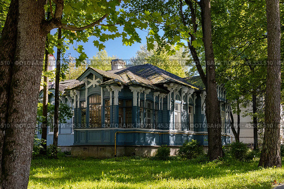Красивый старый деревянный дом в провинциальном городе. Вид с улицы на городской одноэтажный деревянный дом среди деревьев. Архитектура городов России. Город Гатчина, Ленинградская область, Россия. Редакционное фото, фотограф Андрей Степанов / Фотобанк Лори
