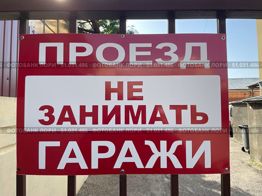 Красно-белая табличка с надписью: "Проезд не занимать. Гаражи". Предупреждение о запрете парковки. Стоковое фото, фотограф Евгений Ковальский / Фотобанк Лори