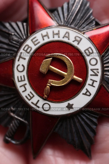 Крупный план центральной части советского ордена Отечественной войны II степени: красная эмаль, символ серпа и молота. Стоковое фото, фотограф Евгений Ковальский / Фотобанк Лори