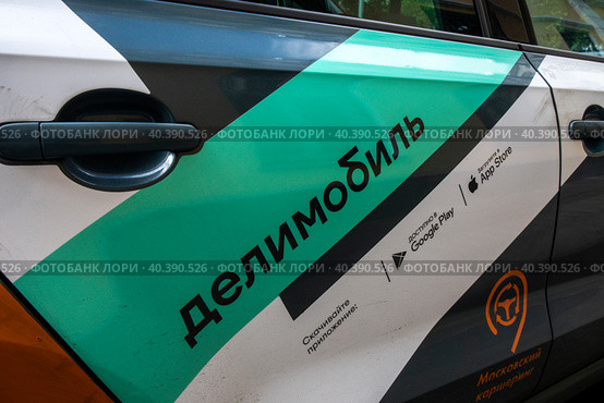 Крупным планом названия компании по аренде автомобилей Делимобиль на улице в центре города Москвы, Россия (2023 год). Редакционное фото, фотограф Николай Винокуров / Фотобанк Лори