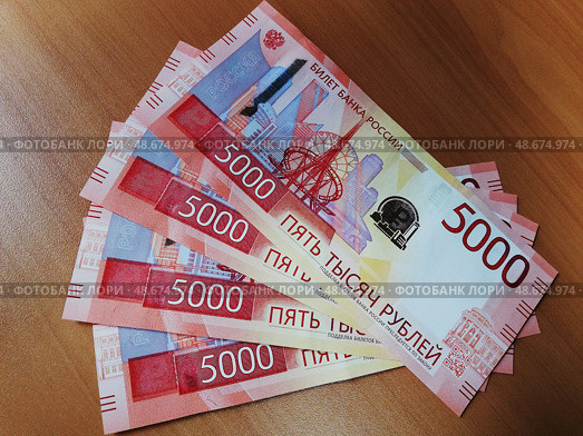 Купюры нового образца 5000 рублей веером на рабочем столе: выручка, доход, зарплата. Стоковое фото, фотограф Ольга Дерябина / Фотобанк Лори