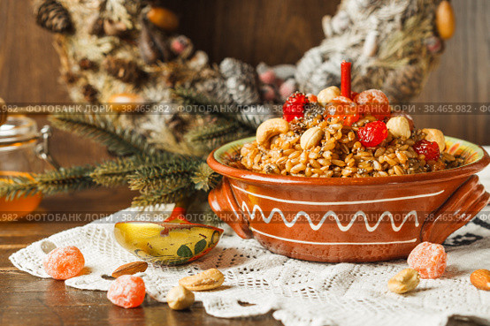 kutya, porridge with honey, nuts and berries, a traditional treat on Christmas Eve. Close-up, with a fir wreath in the background. Стоковое фото, фотограф Bogdanova Mariia / Фотобанк Лори