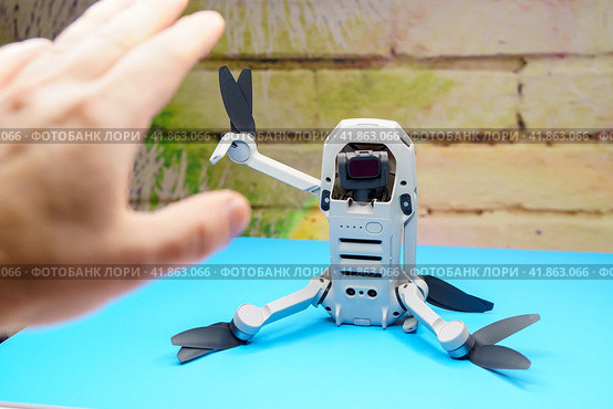 Квадрокоптер Dji Mini 2 сидит на столе и приветствует человека взмахом руки, во время запрета на полеты дронов (2023 год). Редакционное фото, фотограф Sergei Gorin / Фотобанк Лори