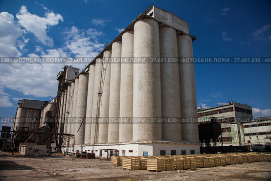Kyzylorda Province, Kazakhstan - April 30, 2019. Outdated Soviet concrete grain elevator. Blue sky, clouds. Стоковое фото, фотограф Alexey Rezvykh / Фотобанк Лори