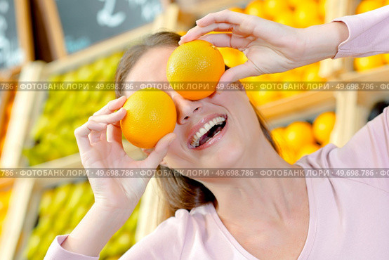 Lady holding oranges in front of her eyes. Стоковое фото, агентство Ingram Publishing / Фотобанк Лори