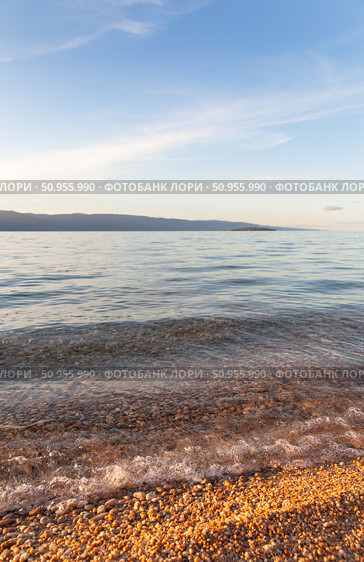 Landscape of Baikal Lake at sunset. Olkhon Island. Sandy and pebbles beach of Small Sea with pure transparent clear water in July hot day. Natural background. Summer travel and seaside recreation. Стоковое фото, фотограф Виктория Катьянова / Фотобанк Лори
