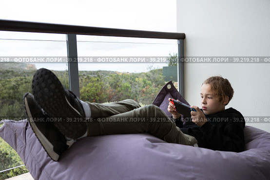 Lazy teenager spending leisure on playing console games. Стоковое фото, фотограф Данил Руденко / Фотобанк Лори
