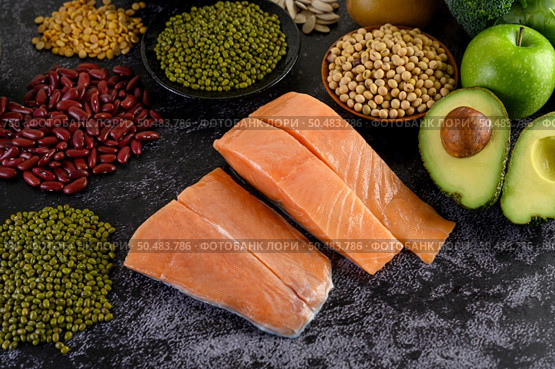 Legumes, fruit, and salmon placed on a black cement floor. Стоковое фото, агентство Ingram Publishing / Фотобанк Лори