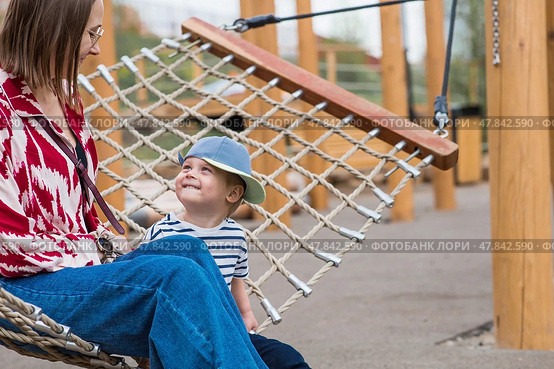 Lifestyle. A cute little boy and his mom are lying in a hammock on a modern outdoor playground. The concept of family privacy and entertainment. Стоковое фото, фотограф Photojuli / Фотобанк Лори