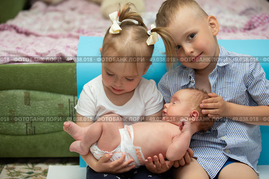 Little brother and sister rejoice at the newborn baby. Three children of different ages in a home environment. The large family. Стоковое фото, фотограф Лазаренко Светлана / Фотобанк Лори