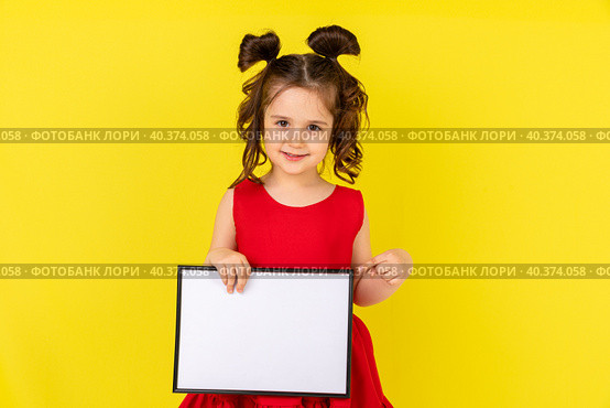 little brunette girl in red drees smiling and holding an empty drawing Board, space for text,isolate on a yellow background. Стоковое фото, фотограф Ирина Михайличенко / Фотобанк Лори