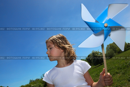 Little girl stood in filed with toy windmill. Стоковое фото, агентство Ingram Publishing / Фотобанк Лори