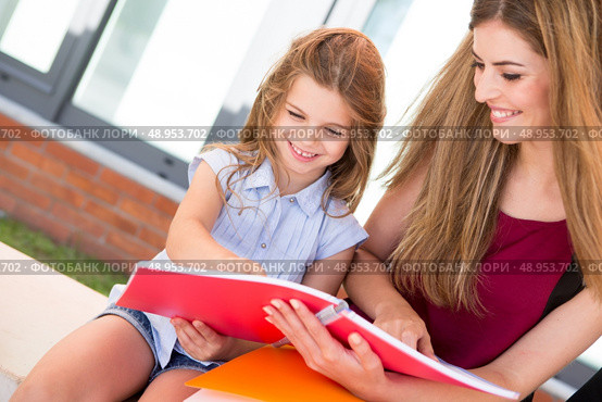 Little school girl showing sketchbook to her mother. Стоковое фото, агентство Ingram Publishing / Фотобанк Лори