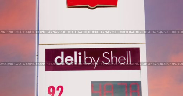 Логотип АЗС Shell с тревожным темно-красным фоном неба. Цены на топливо на путеводителе с логотипом. Shell plc — британская многонациональная нефтегазовая компания. Редакционное видео, видеограф FotograFF / Фотобанк Лори
