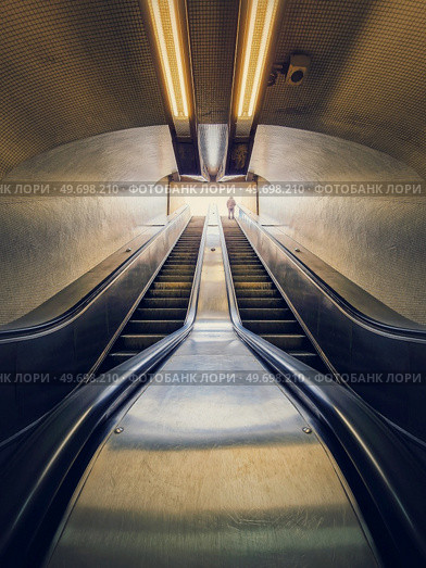 Lone man climbing out on a subway escalator. Symmetrical underground moving staircase. Стоковое фото, агентство Ingram Publishing / Фотобанк Лори