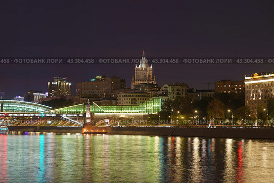 Long exposure photography of Moscow cityscape during autumn night. Blurred lights. Stalinist architecture - building of Ministry of foreign affairs. Bogdan Khmelnitsky Bridge (Kiev Pedestrian Bridge) 2022. Редакционное фото, фотограф YuryKara / Фотобанк Лори