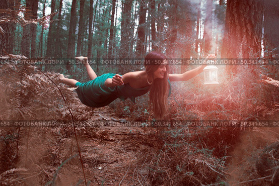 long shot woman levitating forest with lantern. Стоковое фото, агентство Ingram Publishing / Фотобанк Лори
