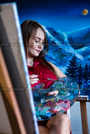 Lovely woman painter in red shirt painting with brush oil paints on canvas in art lab, pensive looking. Portrait of pretty drawing woman artist. Artisanal lifestyle concept. Copy ad text space. Стоковое фото, фотограф Aleksandr Golubev / Фотобанк Лори