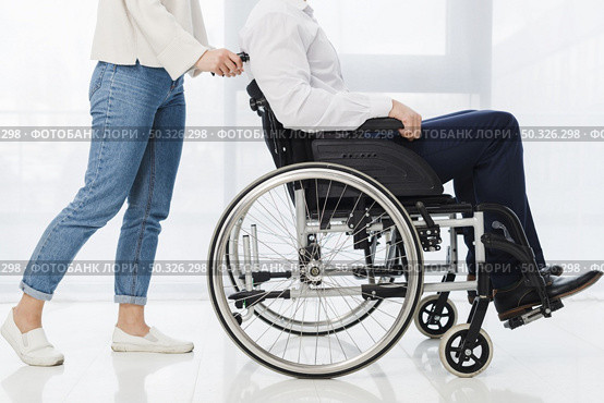 low section woman pushing man sitting wheelchair. Resolution and high quality beautiful photo. low section woman pushing man sitting wheelchair. High quality beautiful photo concept. Стоковое фото, агентство Ingram Publishing / Фотобанк Лори
