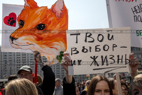 Люди держат плакат против использования меха животных на Первомайском марше в защиту животных по центральным улицам города Москвы, Россия (2019 год). Редакционное фото, фотограф Николай Винокуров / Фотобанк Лори