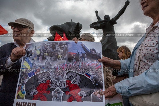 Люди держат плакат против войны на Украине во время митинга против поборов за капитальный ремонт в городе Москве, Россия (2015 год). Редакционное фото, фотограф Николай Винокуров / Фотобанк Лори