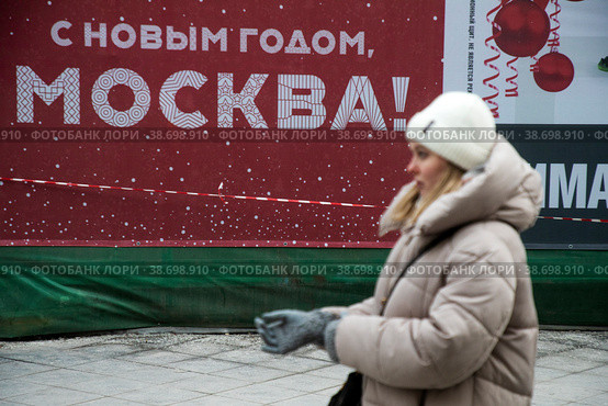Люди идут по Никольской улице в центре города Москвы на фоне баннера поздравлением с Новым годом (2023 год). Редакционное фото, фотограф Николай Винокуров / Фотобанк Лори