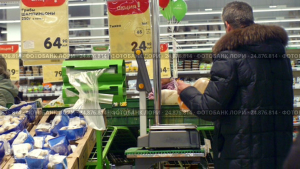 Люди взвешивают фрукты на весах в продуктовом магазине (2017 год). Редакционное видео, видеограф Юлия Зайцева / Фотобанк Лори