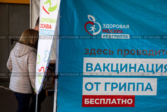Люди записываются на прием в мобильный пункт бесплатной вакцинации от гриппа в специальном автомобиле скорой помощи у метро в городе Москве, Россия (2023 год). Редакционное фото, фотограф Николай Винокуров / Фотобанк Лори