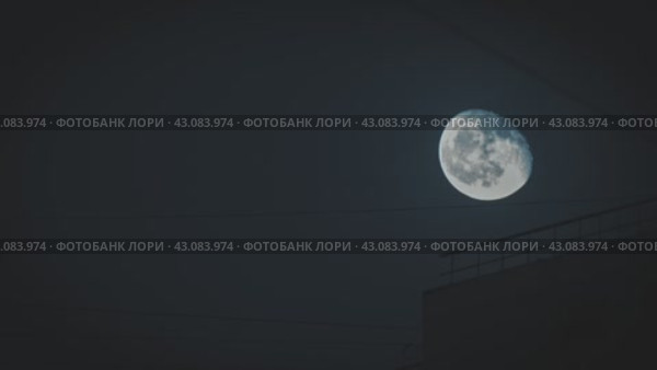 Луна на фоне ночного неба с силуэтом электрического провода и перилами ограждения на крыше здания. Сияние луны контрастирует с окружающей темнотой, создавая безмятежную и спокойную сцену. Стоковое видео, видеограф Воловодов Владимир / Фотобанк Лори