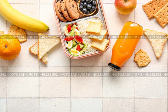 Lunchboxes with delicious food and bottle of juice on white tile background. Стоковое фото, фотограф Pixel_shot / Фотобанк Лори