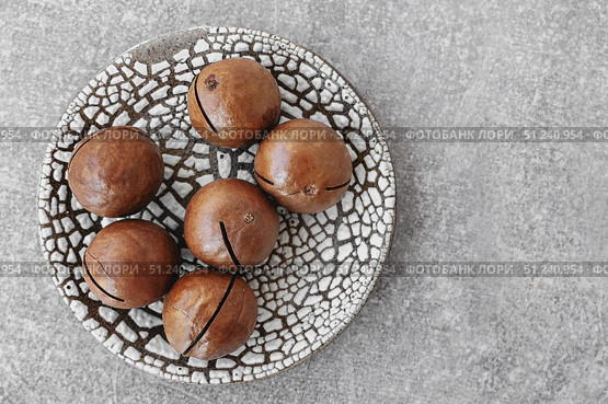 Macadamia. A handful of Macadamia nuts in a handmade plate on the table, top view. Copy space. Стоковое фото, фотограф Оксана Медведева / Фотобанк Лори