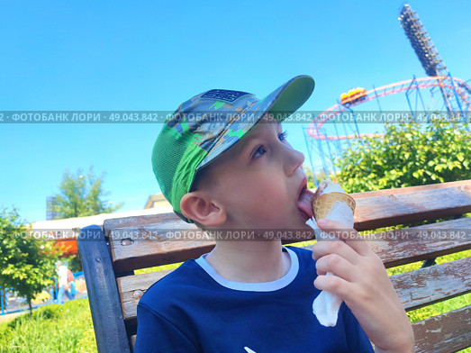 Мальчик кушает мороженое в вафельном стаканчике. A boy eats ice cream in a waffle cup. Стоковое фото, фотограф Денис Баданин / Фотобанк Лори