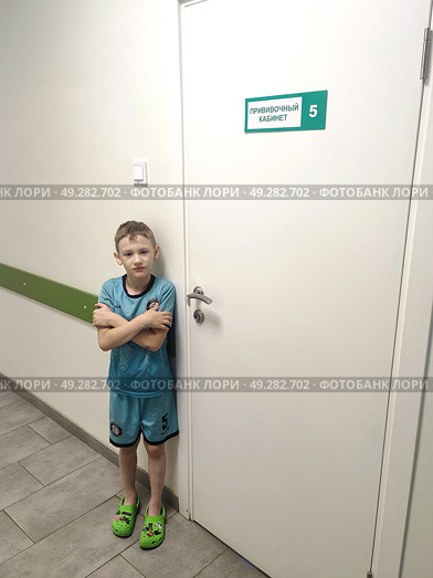 Мальчик стоит перед процедурным кабинетом в поликлинике. A boy stands in front of a treatment room in a polyclinic. Стоковое фото, фотограф Денис Баданин / Фотобанк Лори