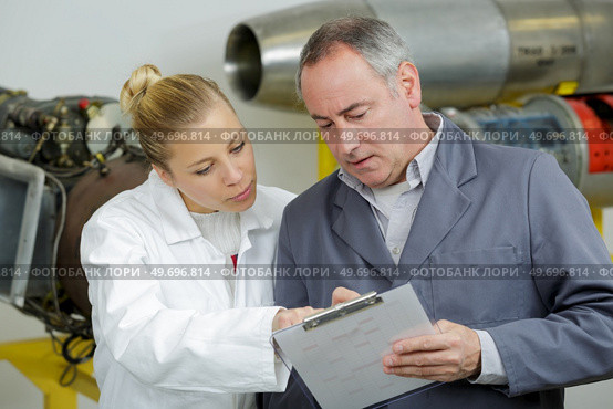 male and female aeronautical engineers conferring over clipboard. Стоковое фото, агентство Ingram Publishing / Фотобанк Лори