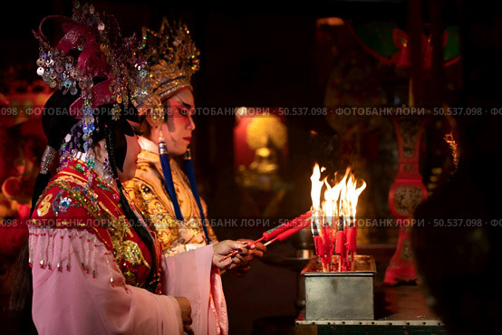 Male and female Chinese opera actors Light a candle to pray homage to the gods to enhance the prosperity for yourself on the occasion of the Chinese New Year festival. Стоковое фото, агентство Ingram Publishing / Фотобанк Лори