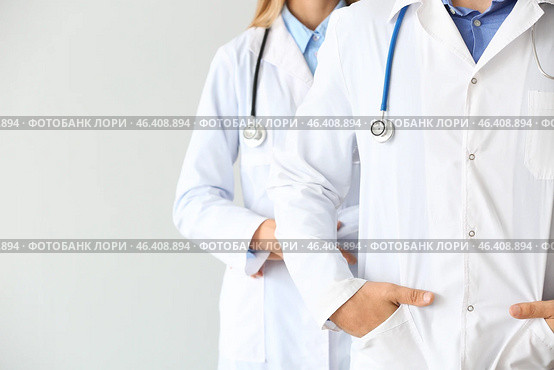 Male and female doctors on light background. Стоковое фото, фотограф Pixel_shot / Фотобанк Лори