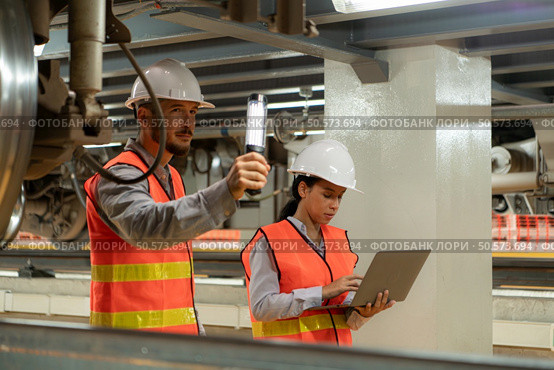 Male and female engineers work together in an electric repair station. Inspecting the undercarriage of electric train that are being repaired at the garage. Стоковое фото, агентство Ingram Publishing / Фотобанк Лори