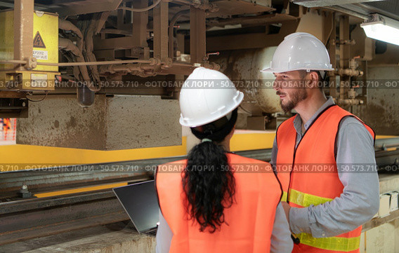 Male and female engineers work together in an electric repair station. Inspecting the undercarriage of electric train that are being repaired at the garage. Стоковое фото, агентство Ingram Publishing / Фотобанк Лори